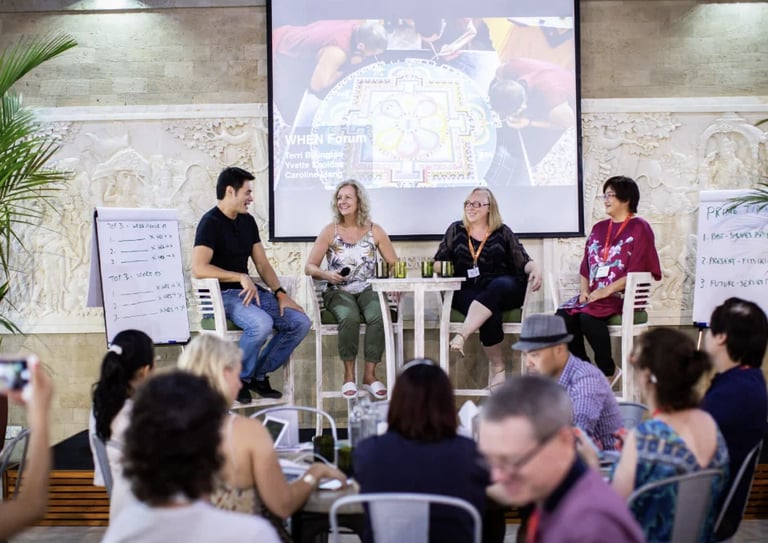 Four panelists seated on stage discussing at a conference